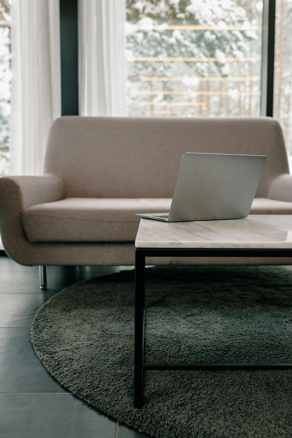 A contemporary living room featuring a laptop on a stylish center table in front of a cozy sofa.