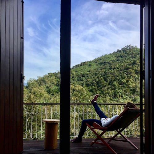 Person In White Long Sleeved Shirt Sitting On Folding Chair One Foot On Railings