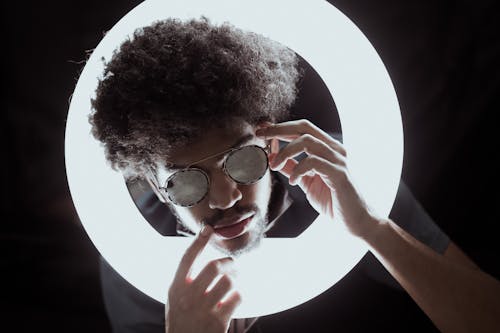 Black man in trendy eyeglasses in glowing ring lamp
