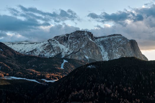 黎明时分，白雪皑皑的山峰在戏剧性的天空下展现出令人惊叹的山地景观
