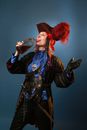 Model in pirate costume with rum on gray background