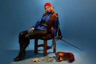 Drunk woman in bandana and glove with skeleton ornament napping on chair against empty bottle on blue background