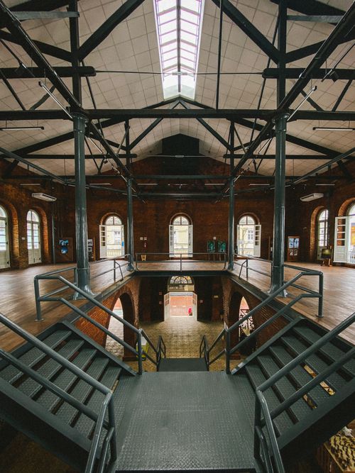 Free Spacious industrial interior with metal stairs and arched windows, perfect for modern architecture lovers. Stock Photo