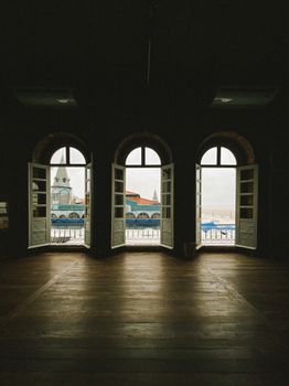 Three arched windows with open shutters reveal a stunning cityscape panorama.