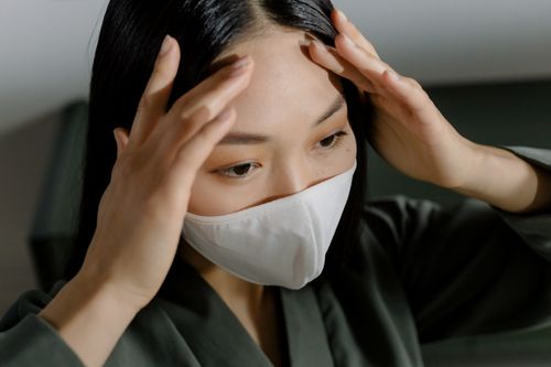 Free Portrait of an Asian woman wearing a protective mask, focusing on safety and virus prevention indoors. Stock Photo