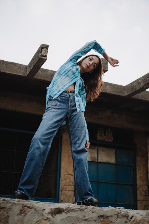 Young woman in denim outfit standing on concrete barrier