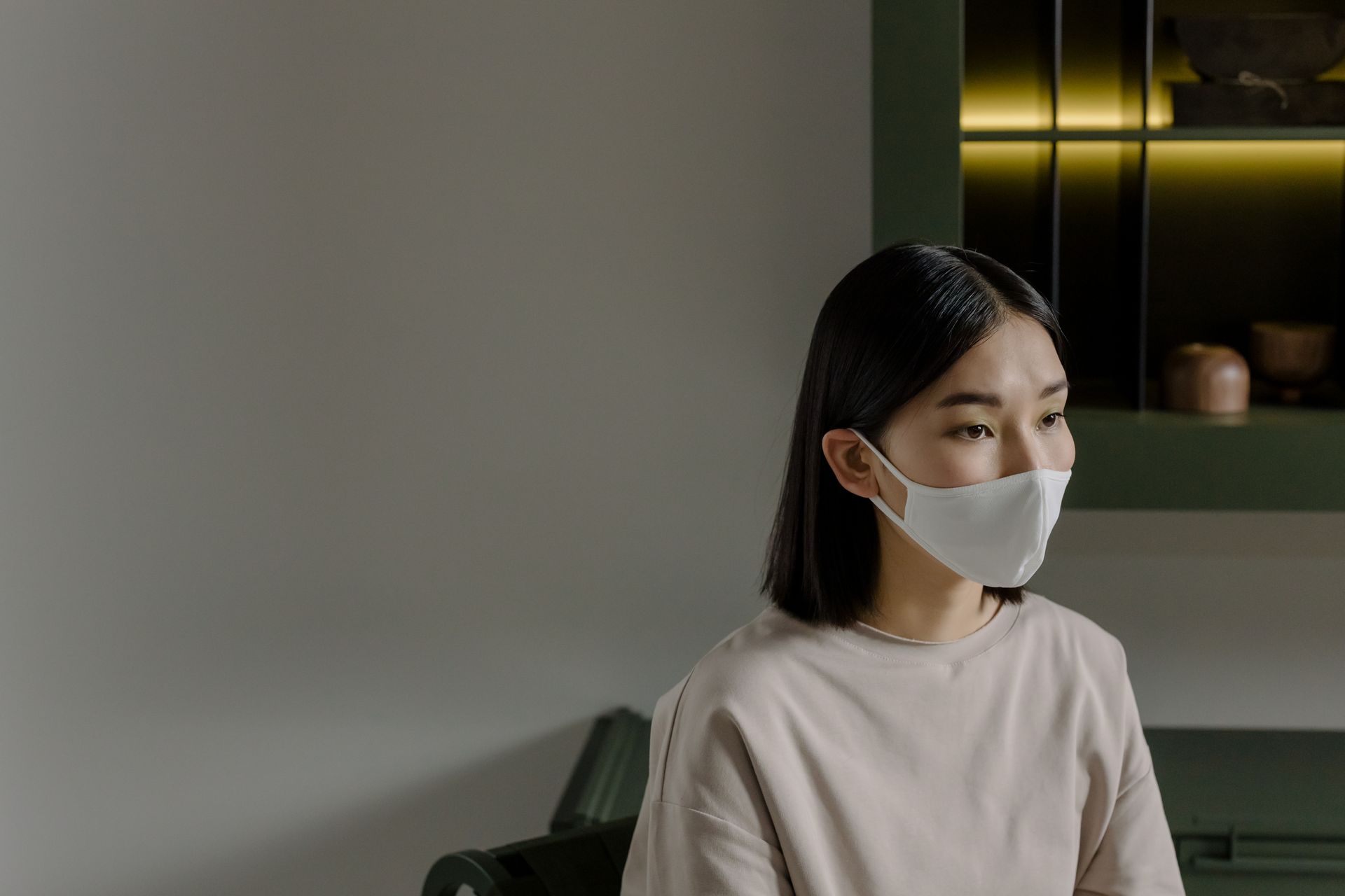 Asian woman wearing a white face mask indoors, focusing on health safety measures.
