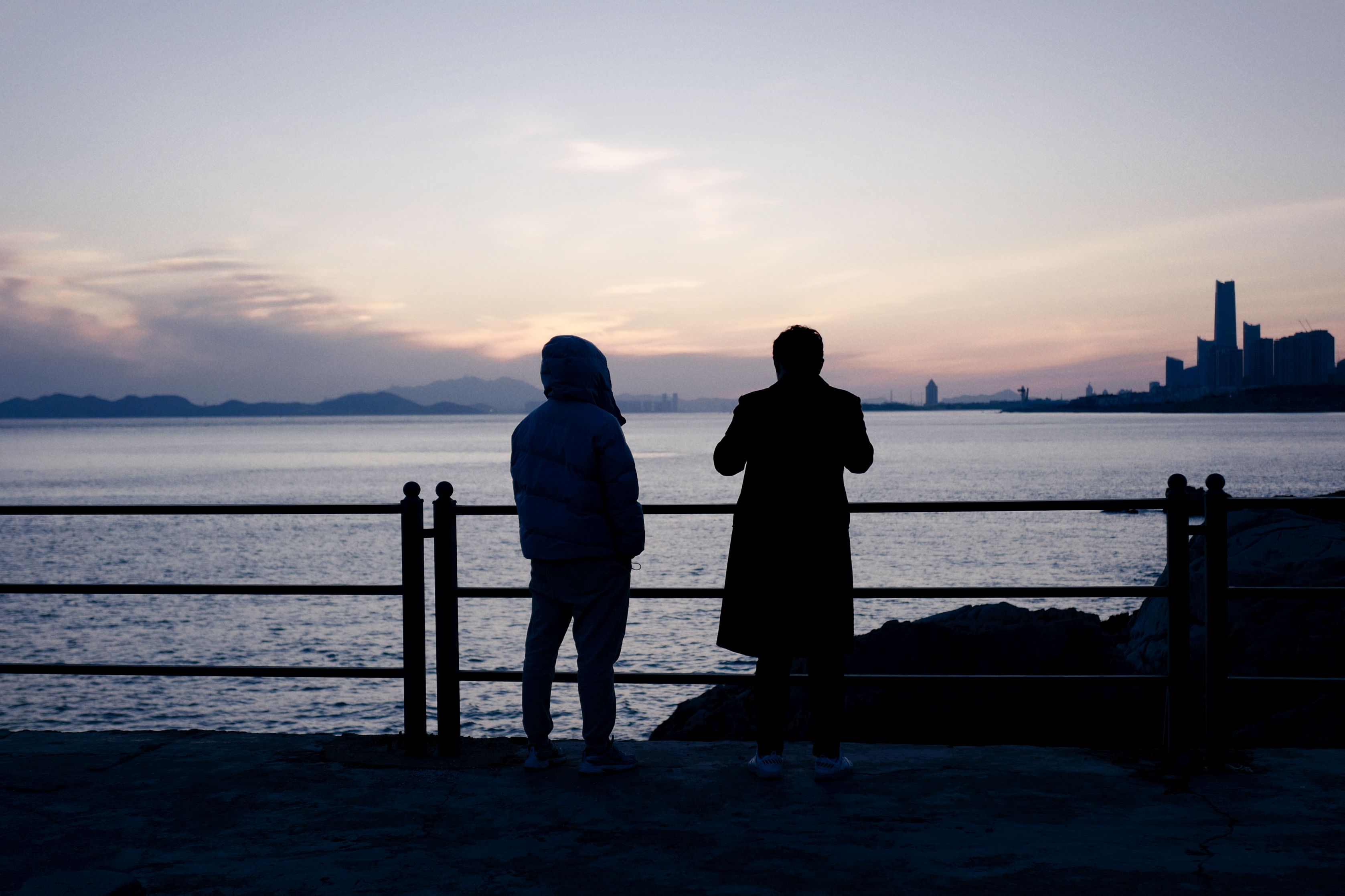 A Silhouette of People Standing Near the Sea · Free Stock Photo