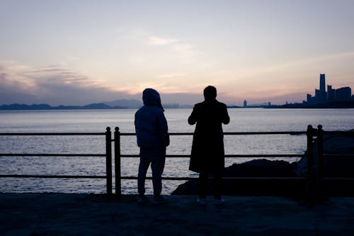 A Silhouette of People Standing Near the Sea
