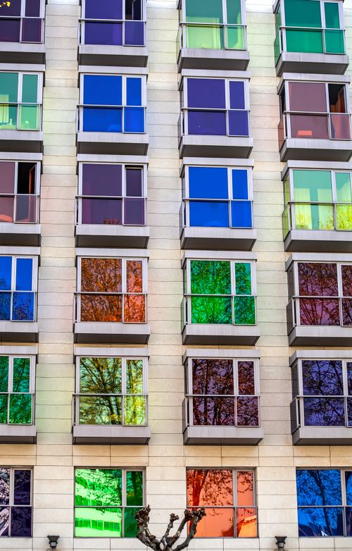 Free Facade of a modern building in Bilbao featuring vivid, colorful glass windows reflecting the cityscape. Stock Photo