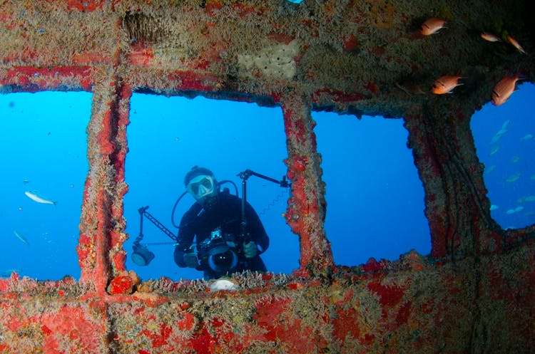 Underwater Photograph Of A Diver With Red Wreck