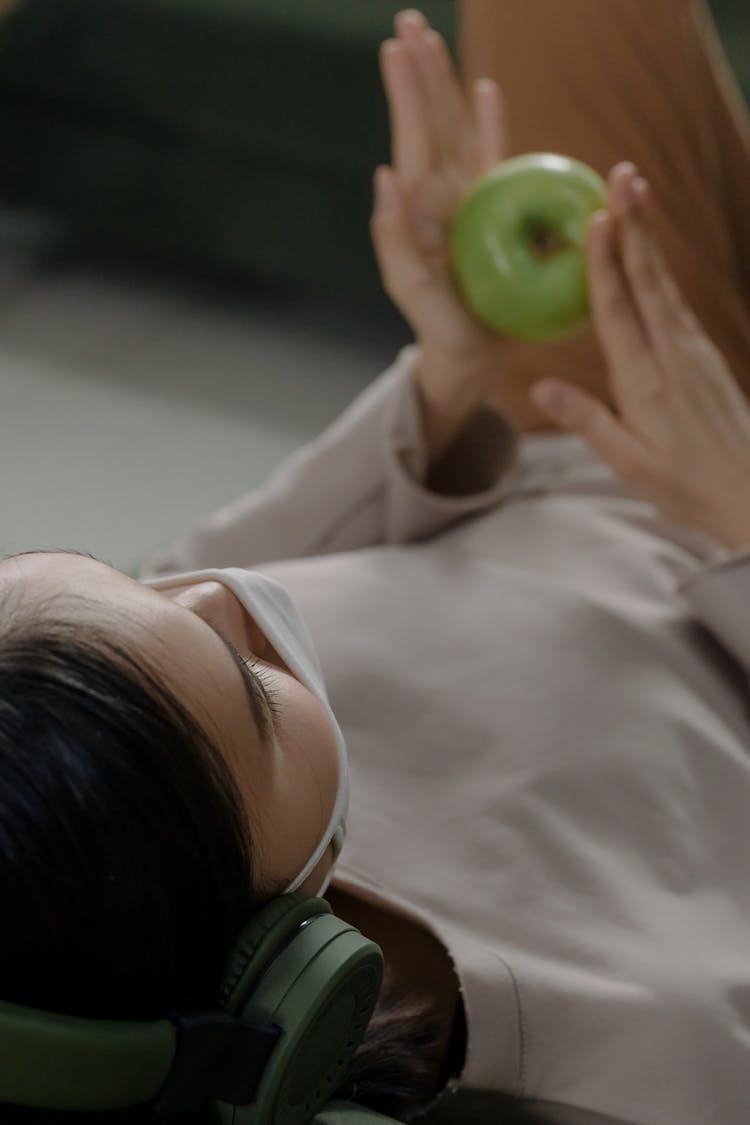 Woman Wearing Headset Holding An Apple