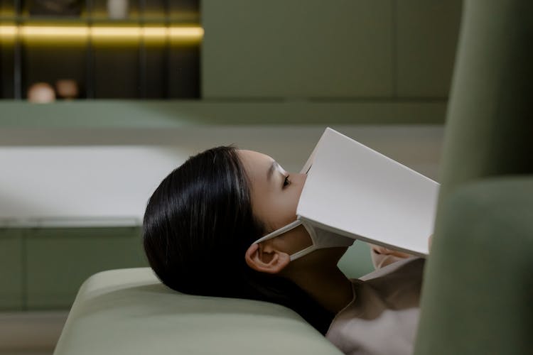 Woman Covering Mouth With Book