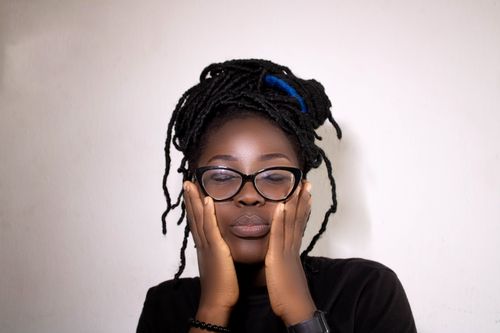 Free A serene portrait of a woman with closed eyes and glasses, set against a white background. Stock Photo