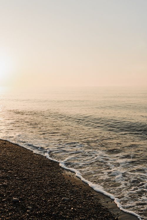 Free Peaceful seaside view at sunrise, capturing gentle waves and a calm horizon. Stock Photo