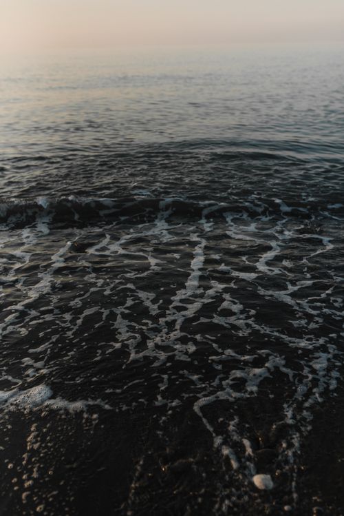 Free Serene seashore at dusk with gentle waves and soft lighting, perfect for nature relaxation. Stock Photo