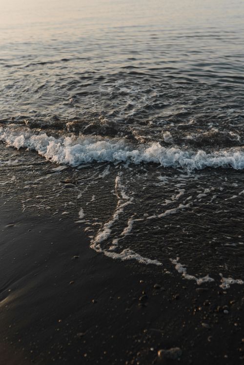 Free Capturing a tranquil wave gently crashing on a sandy beach at sunset, embodying serene coastal beauty. Stock Photo