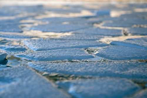 Free A detailed close-up of cracked ice floating on water, capturing a winter scene with a cold, frosty atmosphere. Stock Photo