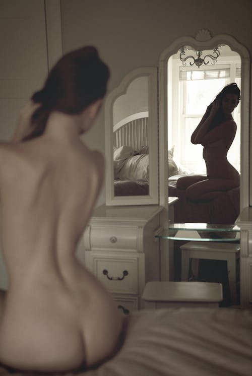 Back View of a Naked Woman Looking at the Mirror