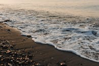 这是一个宁静的场景，捕捉到了宁静的日落期间，海浪轻轻地冲刷着卵石海岸