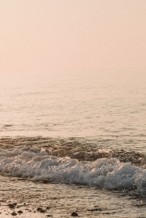 Free Gentle waves crashing against the shore at sunset, capturing the serenity of the beach. Stock Photo