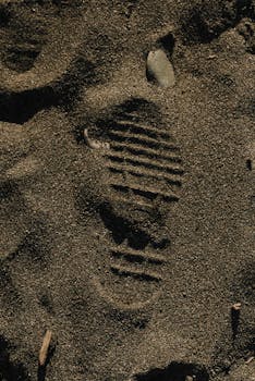 Close-up of a boot imprint in sand, capturing texture and natural patterns.