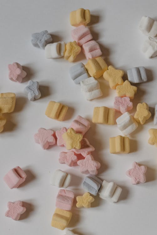 Top view delicious multicolored marshmallows in shape of small stars scattered on white table