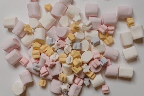 Many tasty marshmallows heaped on white table