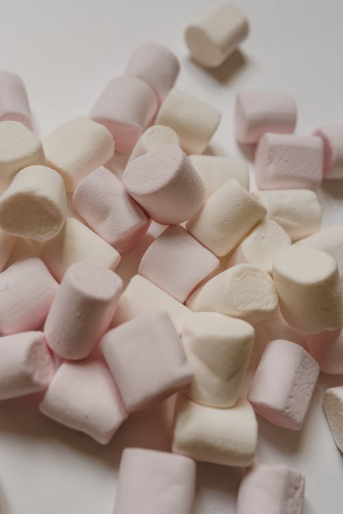 Free From above delicious yummy light marshmallows in cylindrical shapes scattered on white table Stock Photo