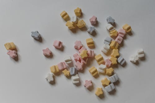 Top view composition of multicolored sweet marshmallows in shape of stars scattered on white surface