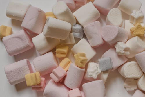 Delicious marshmallows heaped on white table