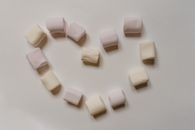 Sweet marshmallows arranged on table in shape of heart