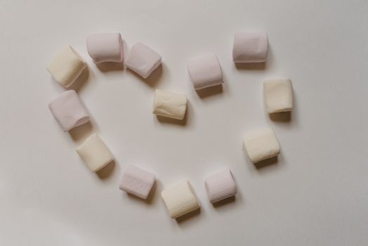 Sweet marshmallows arranged on table in shape of heart