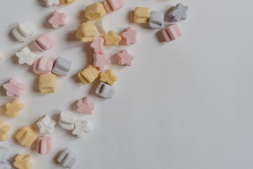 Free Top view arrangement of multicolored yummy marshmallows in shape of stars scattered in corner of white paper Stock Photo