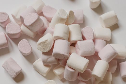 Top view arrangement of sweet delicious marshmallows of light color heaped on white surface