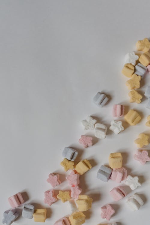 Colorful marshmallows scattered on white table corner