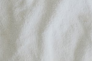 Top view full frame of soft white towel fabric placed on table in light room