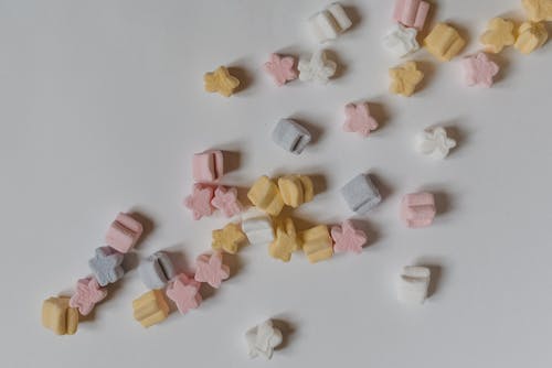 Top view composition of sweet yummy marshmallows in shape of stars scattered on white surface