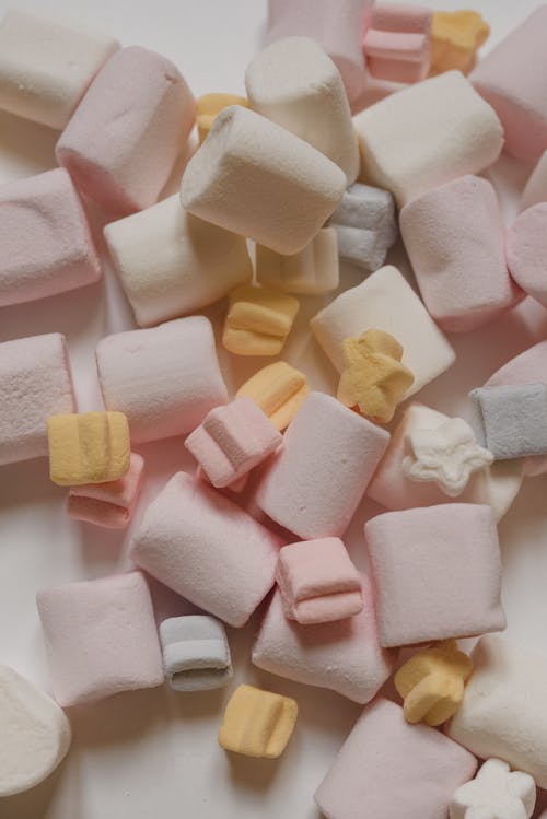 Free Top view yummy delicious marshmallows of different shapes and colors heaped on white table Stock Photo