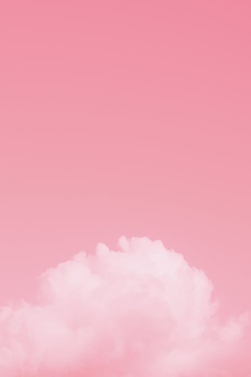 Bright pink colorful sky with white soft fluffy cumulus clouds floating in daylight