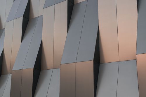 Free Close-up of a modern building facade with abstract geometric patterns and smooth textures. Stock Photo