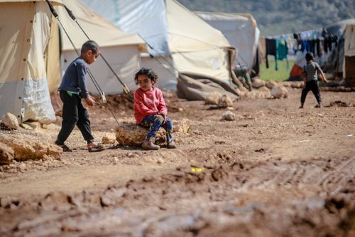 Free Children sitting in a refugee camp in Idlib, Syria on a sunny day. Stock Photo