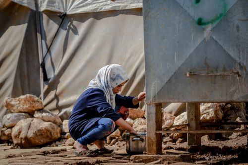 Free A woman in a hijab collects water in a refugee camp in Idlib, Syria. Stock Photo