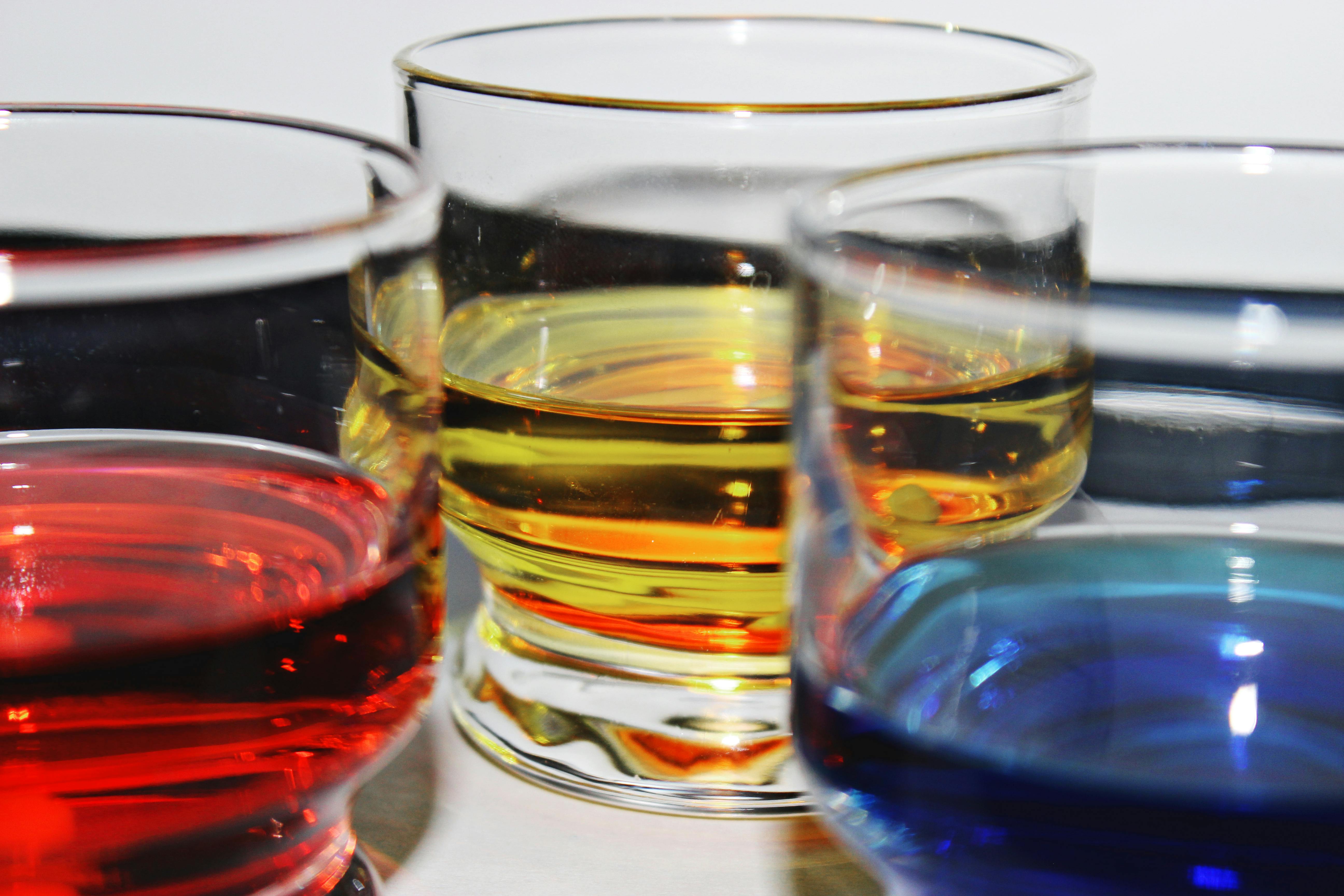 Close-up of glassware filled with colorful liquids in red, blue, and yellow hues.
