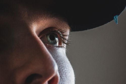 Free Detailed close-up photo of a young man's eye partially shaded by a hat, capturing intense expression. Stock Photo