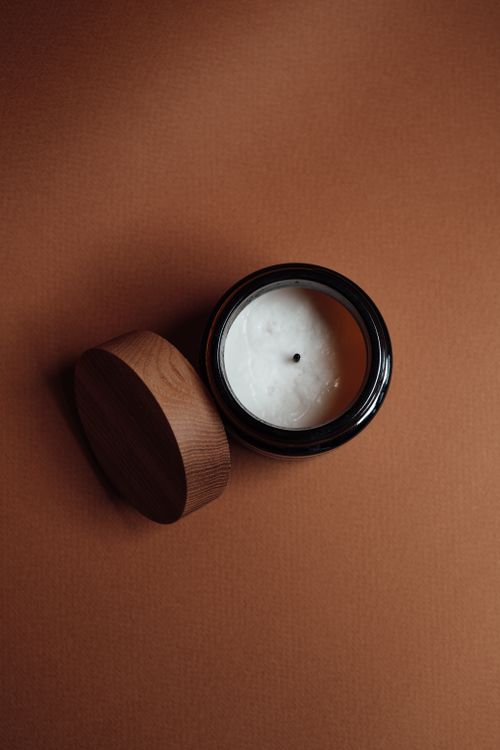 Free Top view of a candle in a jar with a wooden lid on a textured brown background. Stock Photo