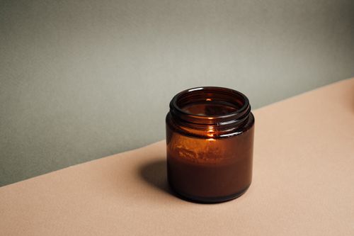 Free A minimalist brown glass container sits elegantly on a beige surface, offering a warm, eco-friendly vibe. Stock Photo