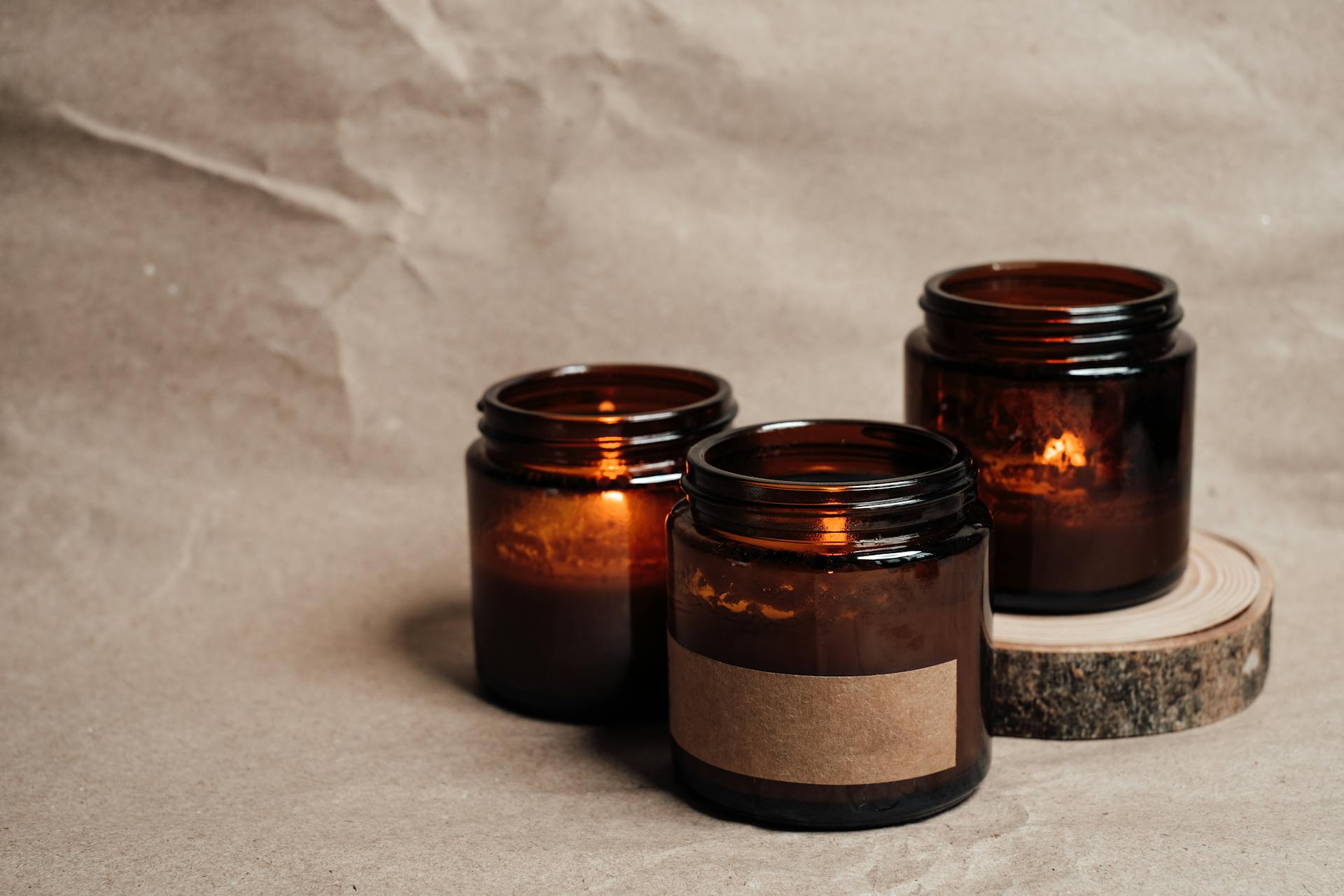 Warm glow of candles in glass jars creating a cozy atmosphere on a neutral background.