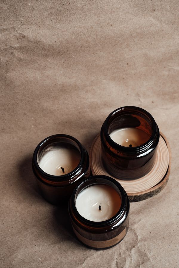 Three amber glass candles on kraft paper — Vie Studio on Pexels