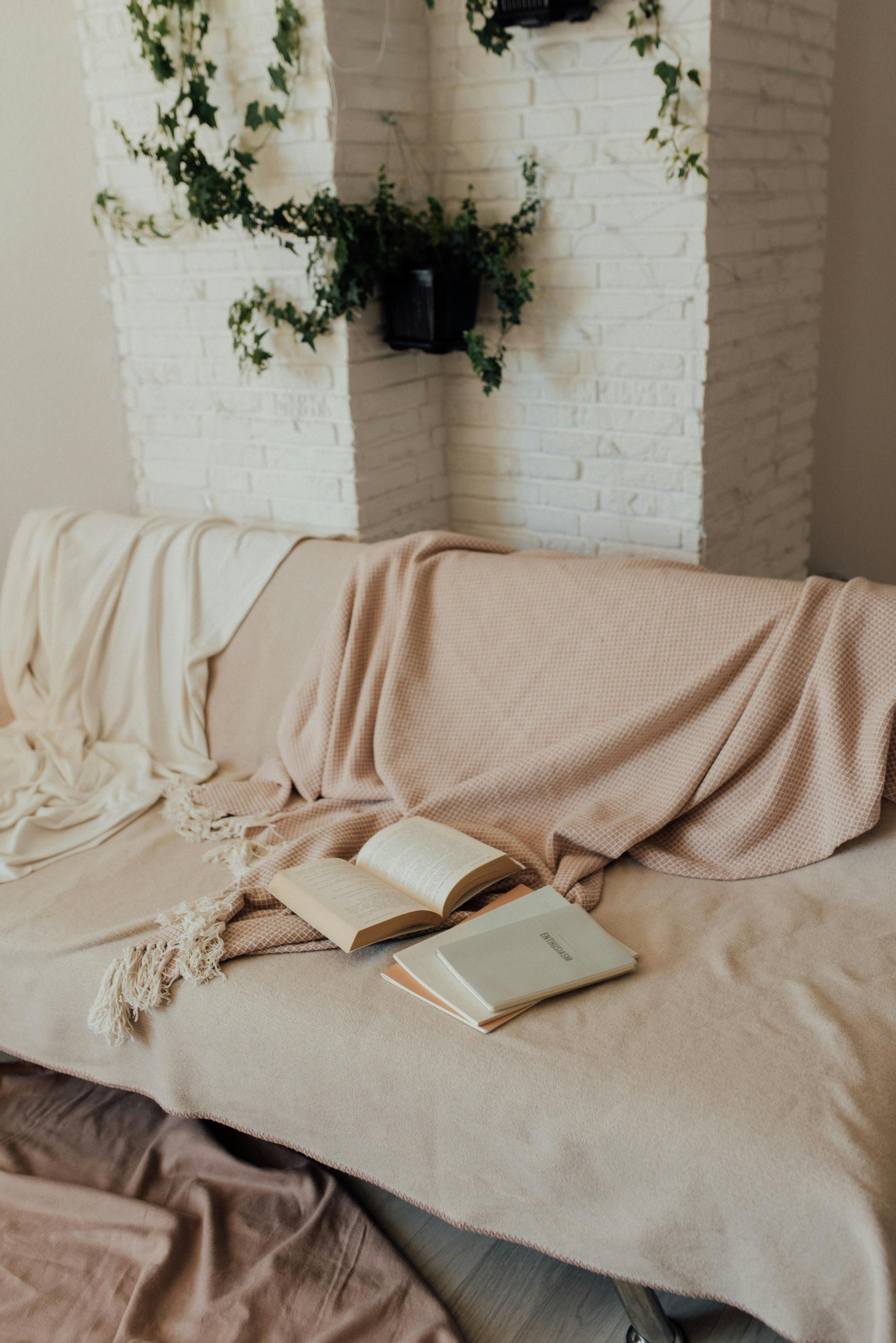 Warm and inviting living room scene with soft blankets and open books on a couch.